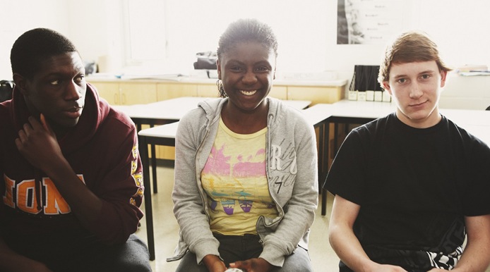 three students in chairs smiling