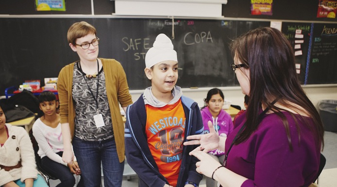 2 teachers coaching a student infront of classmates